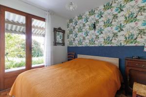 a bedroom with a bed and a window with floral wallpaper at Villa L'Andélu - Conciergerieland in Saint-Michel-Escalus