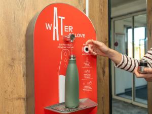a person taking a picture of a water bottle at ibis Orange Centre Echangeur A7 A9 in Orange