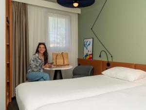 a woman sitting at a table in a hotel room at ibis Orange Centre Echangeur A7 A9 in Orange +96 photos