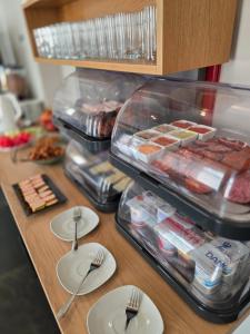a counter with plates and utensils on a table with food at Inter Hotel in Debrecen +25 photos