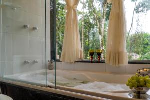 a bath tub with two glasses of wine in a bathroom at Pousada 3 Bacias Penedo in Penedo