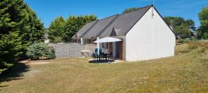 a small white house with a table and an umbrella at Résidence le safran in Erdeven