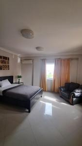 a bedroom with a bed and a couch and a window at Sea View Haven in Accra
