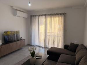 a living room with a couch and a large window at 11 Rose in Sannat