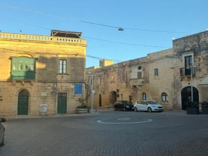 a street with two old buildings and a white car at 11 Rose in Sannat