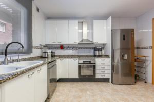 a kitchen with white cabinets and a stainless steel refrigerator at Duplex Beach Masnou in El Masnou