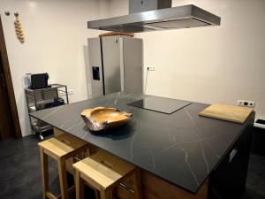 a kitchen with a black counter top with stools at Villa La Roca con casita independiente in Guadarrama