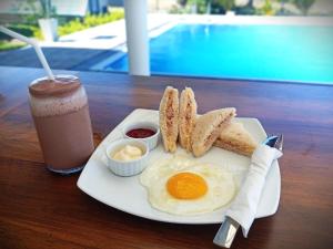a breakfast plate with eggs and bread and a drink at Pini Villa in Ampara