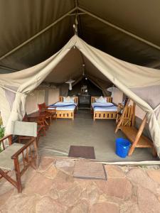 a tent with two beds and chairs in it at Maasai Wild Adventure in Gatunga