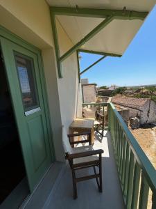 a balcony of a house with chairs and a door at To Ampeli in Potamós
