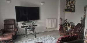 a living room with a flat screen tv and chairs at Rest & Nest in Chelsfield