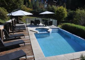 a swimming pool with chairs and umbrellas in a yard at Hostería Verde Morada in Villa La Angostura