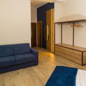 a living room with a blue couch and a bed at Prima Classe Battipaglia in Battipaglia