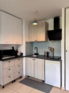 a kitchen with white cabinets and a black counter top at Le Lobellia à Sainte Clotilde centre in Sainte-Clotilde
