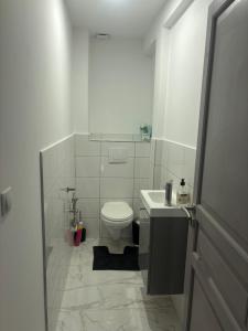 a white bathroom with a toilet and a sink at Le 21 Comfortable townhouse in Morhange