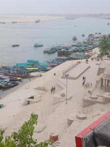 a group of people walking on a beach next to the water at KHS ROOMs near ghat and temples in Varanasi