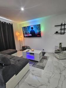 a living room with a couch and a tv on the wall at Le 21 Comfortable townhouse in Morhange