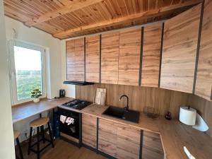 a kitchen with wooden cabinets and a sink at Dom Pod Niebem in Świętajno +4 photos