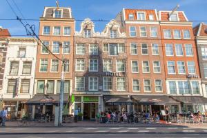 a large brick building with people sitting outside of it at ibis Styles Amsterdam Central Station in Amsterdam