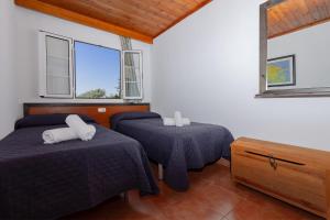 a bedroom with two beds and two windows at Bon repós B11 in Cala en Bosc