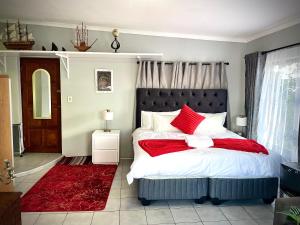 a bedroom with a large bed with red pillows at Pinnacle Pearl View Cottage in Johannesburg
