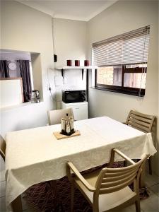 a kitchen with a table and chairs with a white table cloth at Pinnacle Pearl View Cottage in Johannesburg