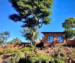 a brick house with a tree in a garden at Pinnacle Pearl View Cottage in Johannesburg
