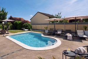 a swimming pool with tables and chairs and umbrellas at Le Garage & Spa Silver in Gondreville