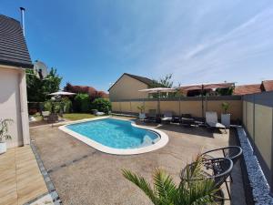 a swimming pool in a yard with chairs and umbrellas at Le Garage & Spa Silver in Gondreville
