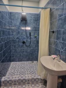 a blue tiled bathroom with a sink and a shower at Rancho Primavera in Cuatro Esquinas