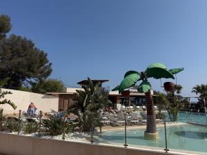 ein Swimmingpool mit einer Palme neben einem Ferienresort in der Unterkunft Ethan in Saint-Raphaël