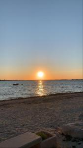 a sunset on the beach with a boat in the water at Villa tra le dune di Campomarino in Campomarino