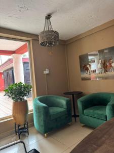 a living room with two green chairs and a chandelier at 247Hotel Apartments in Accra