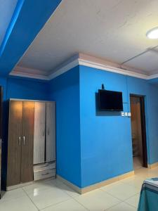 a room with a blue wall with a cabinet and a tv at 247Hotel Apartments in Accra