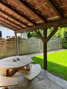 a picnic table and bench under a wooden pergola at Garden House Interlaken in Interlaken