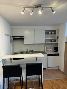 a kitchen with white cabinets and a sink and two chairs at Garden House Interlaken in Interlaken