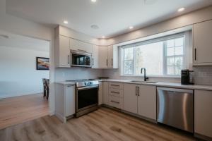 a kitchen with white cabinets and a sink and a window at Cherry Lane Cottage | 3 Bed & 2 Bath in Foxtrap