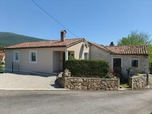 a small white house with a stone wall at Haus Stepcich in Plomin