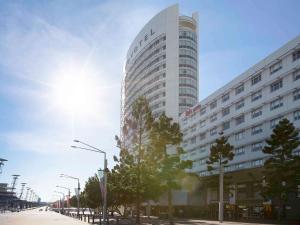 a tall white building with the sun behind it at Novotel Sydney Olympic Park in Sydney