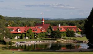 a building with a red roof next to a lake at The Highlands at Harbor Springs in Harbor Springs