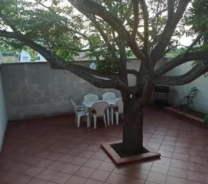 a patio with a tree and tables and chairs at Villa tra le dune di Campomarino in Campomarino