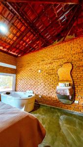 a bedroom with a bed and a tub in a brick wall at Solar do Ouro in São Thomé das Letras