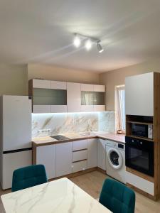 a kitchen with white cabinets and blue chairs at Vivat in Berehove