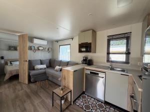 a kitchen and a living room with a couch and a table at La Cabane in Claouey