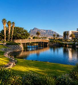a bridge over a river with palm trees and mountains at ZALS- Nine Palms -Luxury Two Bed in Cape Town
