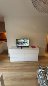 a flat screen tv sitting on top of a white dresser at Bagnole de l'Orne Studio in Bagnoles de l'Orne