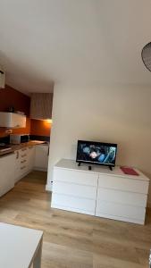 a living room with a flat screen tv on a white table at Bagnole de l'Orne Studio in Bagnoles de l'Orne +6 photos