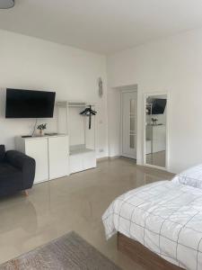 a white bedroom with a bed and a flat screen tv at Am Goethe Bogen in Zeuthen