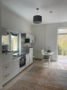 a kitchen with white cabinets and a table with a chair at Am Goethe Bogen in Zeuthen