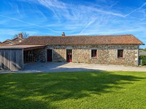 a stone house with a red door and a yard at Domaine de Beau Site in Peyrat-de-Bellac